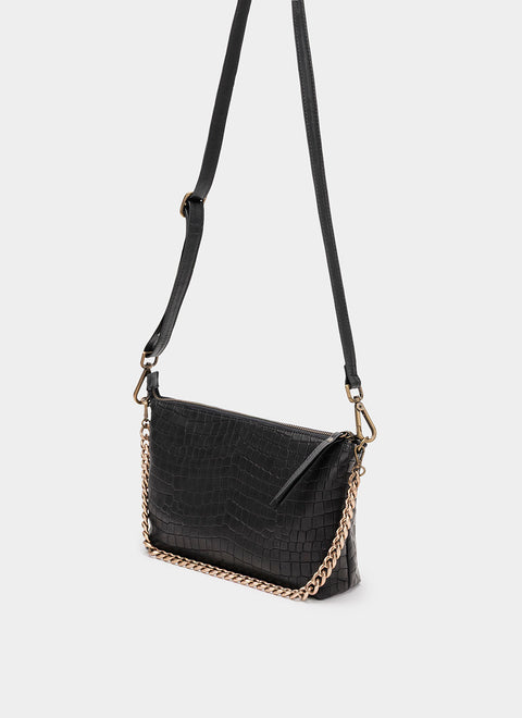 Vista lateral de bolso negro de piel mostrando su textura grabada y acabado artesanal.