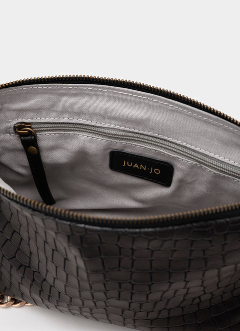 Detalle interior de bolso negro de piel con acabados de calidad y bolsillo interior.