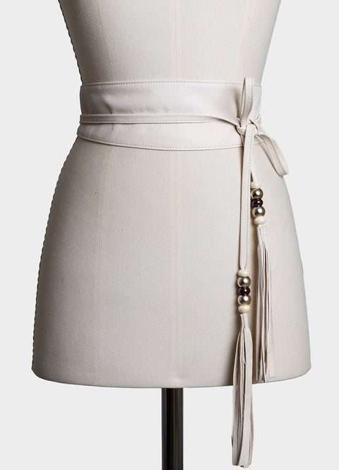 cinturón fajín de piel de cordero color blanco, anudado con dos tiras terminadas con unas bolitas de cristal de colores y un tasel de flecos de la misma piel