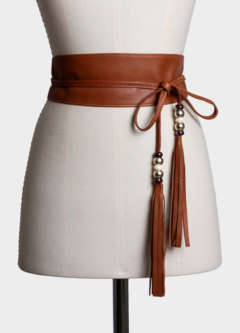 cinturón fajín de piel color marrón claro, anudado y con unos adornos con bolas de cristal y flecos de la misma piel