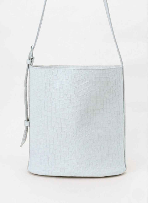 Bolso color blanco de piel grabada en dibujo cocodrilo. Forma de cubo y con asa regulabe con una hebilla. 