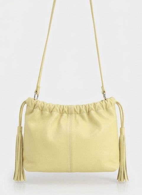 bolso de piel en color amarillo pastel, con asa extraible para usar como bandolera o como clutch. con frunce en parte superior y flecos a los lados de la misma piel