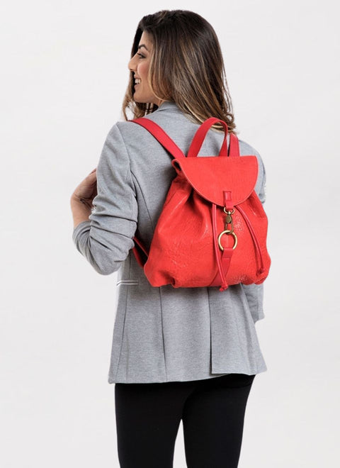 Una modelo lleva a la espalda la mochila de cuero Rojo Oslo. Esta mochila está confeccionada en nuestro taller con un precioso cuero flexible con relieve. Es una mochila de tamaño mediano. Con un asa superior para cogerla con la mano. Se cierra abrochando dos tiras de piel y con un mosquetón metálico dorado.