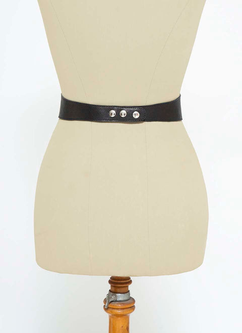 Visión posterior de un maniquí con un cinturón corset piel de color negro. Se ven los broches para poner y quitar el cinturón facilmente.
